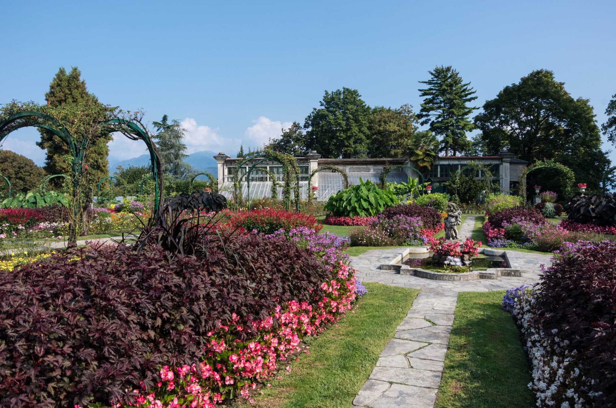 Giardino fiorito con sentiero e fontana.