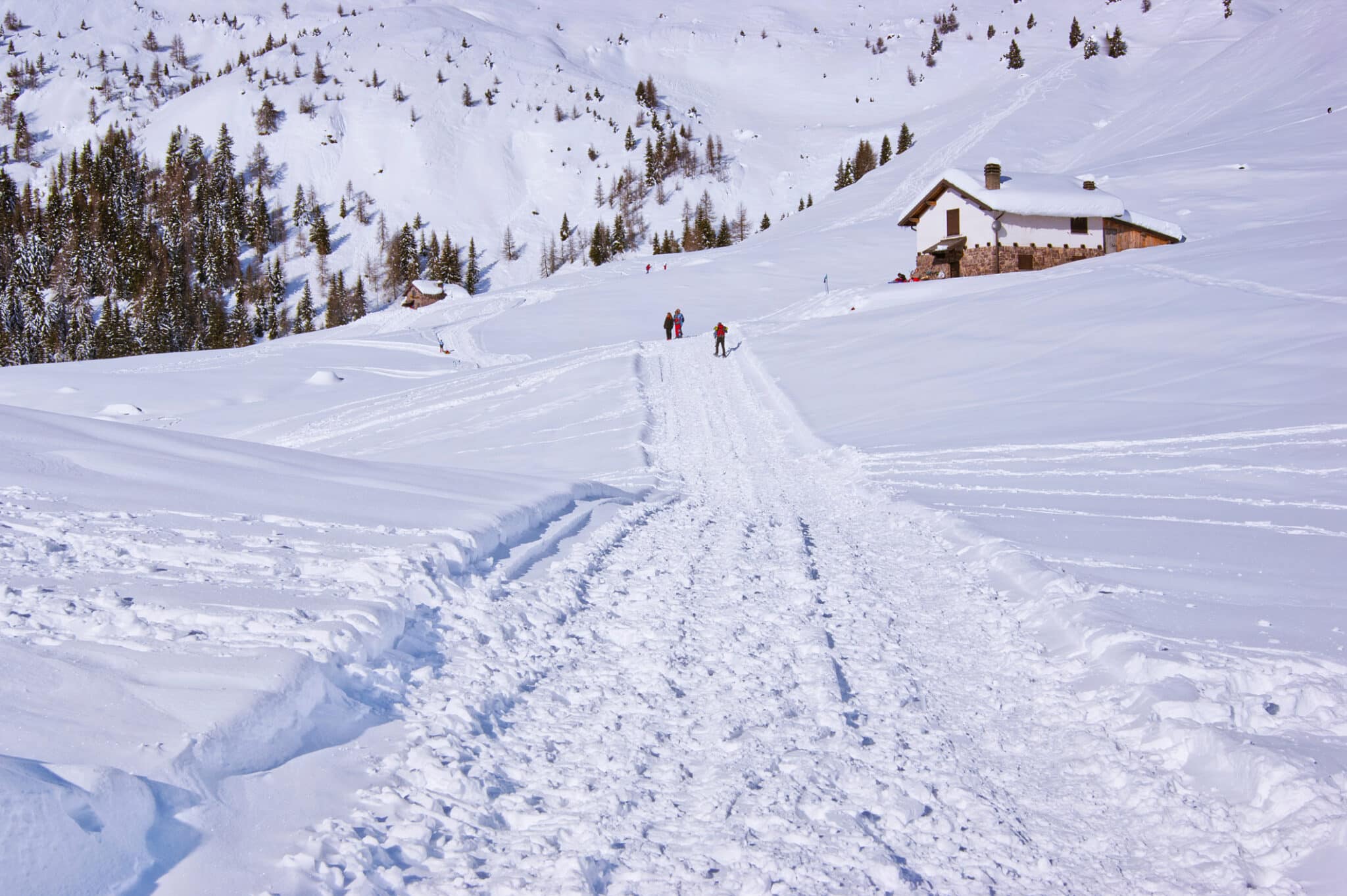 Persone che camminano su sentiero innevato con chalet