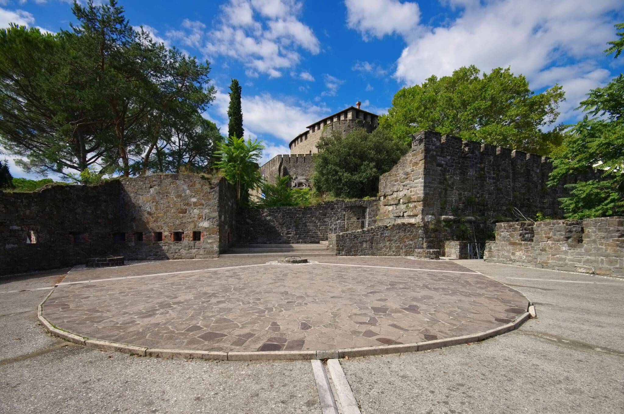 Castello antico con alberi sotto cielo azzurro.