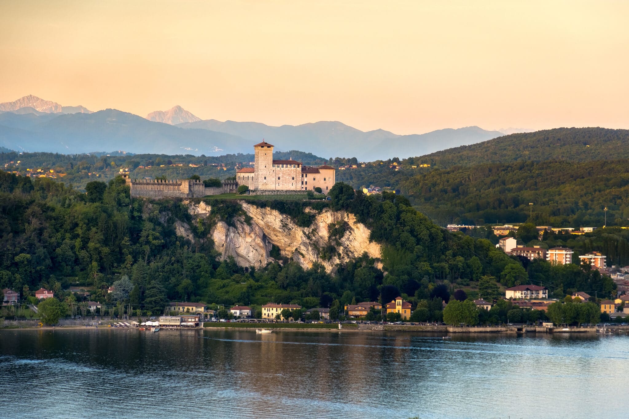 Castello arroccato su scogliera al tramonto, lago antistante