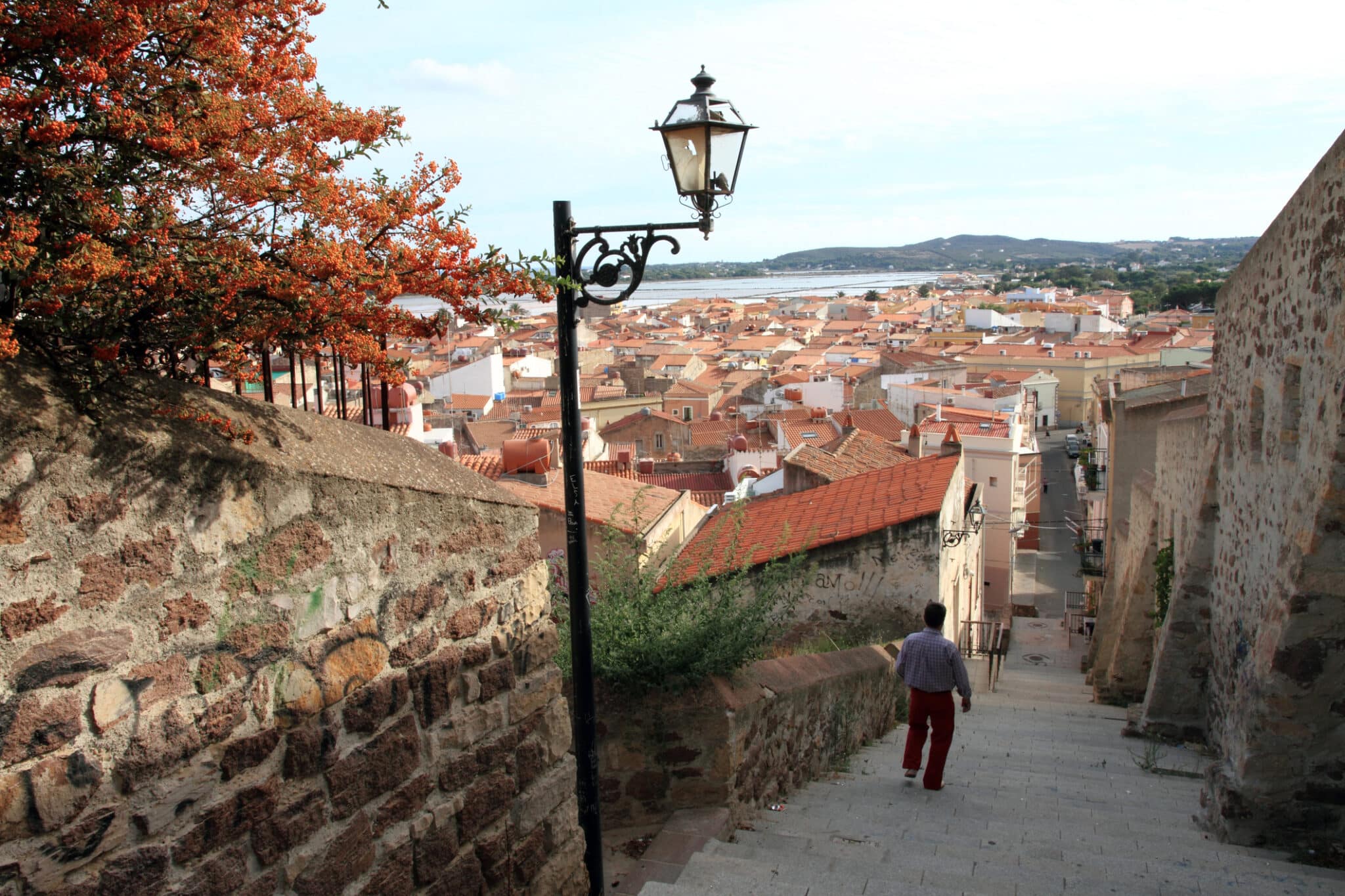 Uomo scende scala verso città europea vista mare