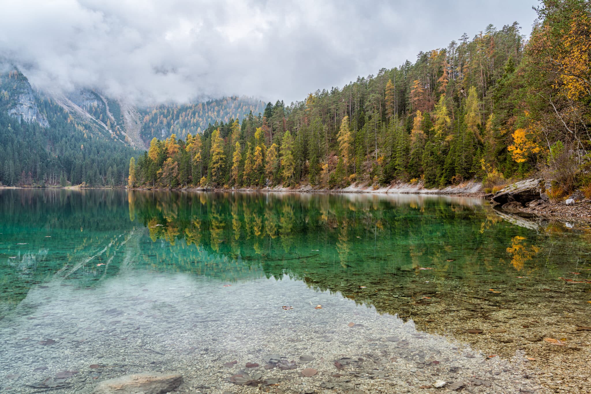 Lago alpino cristallino circondato da foreste autunnali