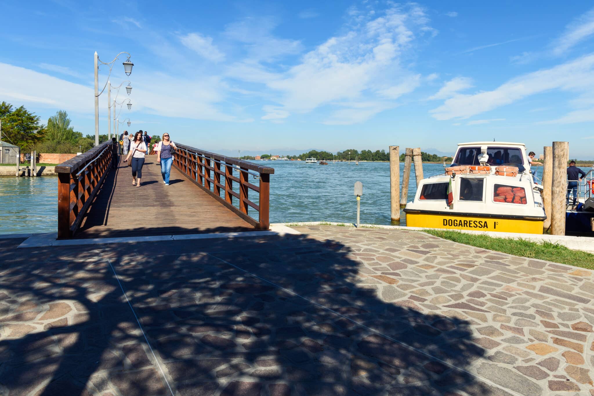 Ponte sul canale con barca e pedoni, cielo sereno