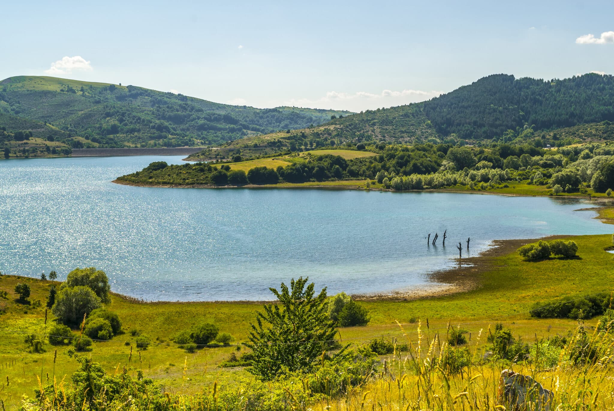 Lago circondato da colline verdi con persone a piedi