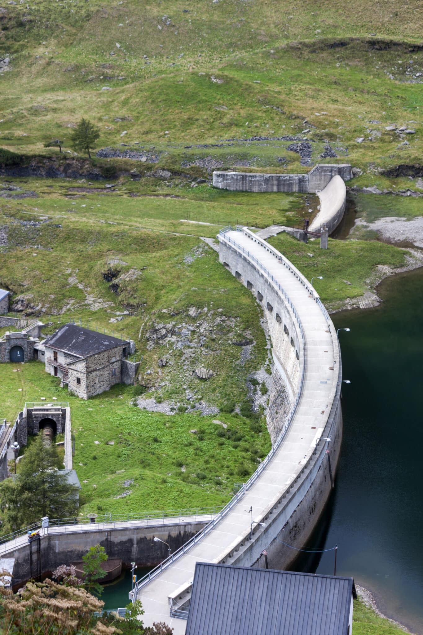 Diga in montagna con edifici storici e lago alpino