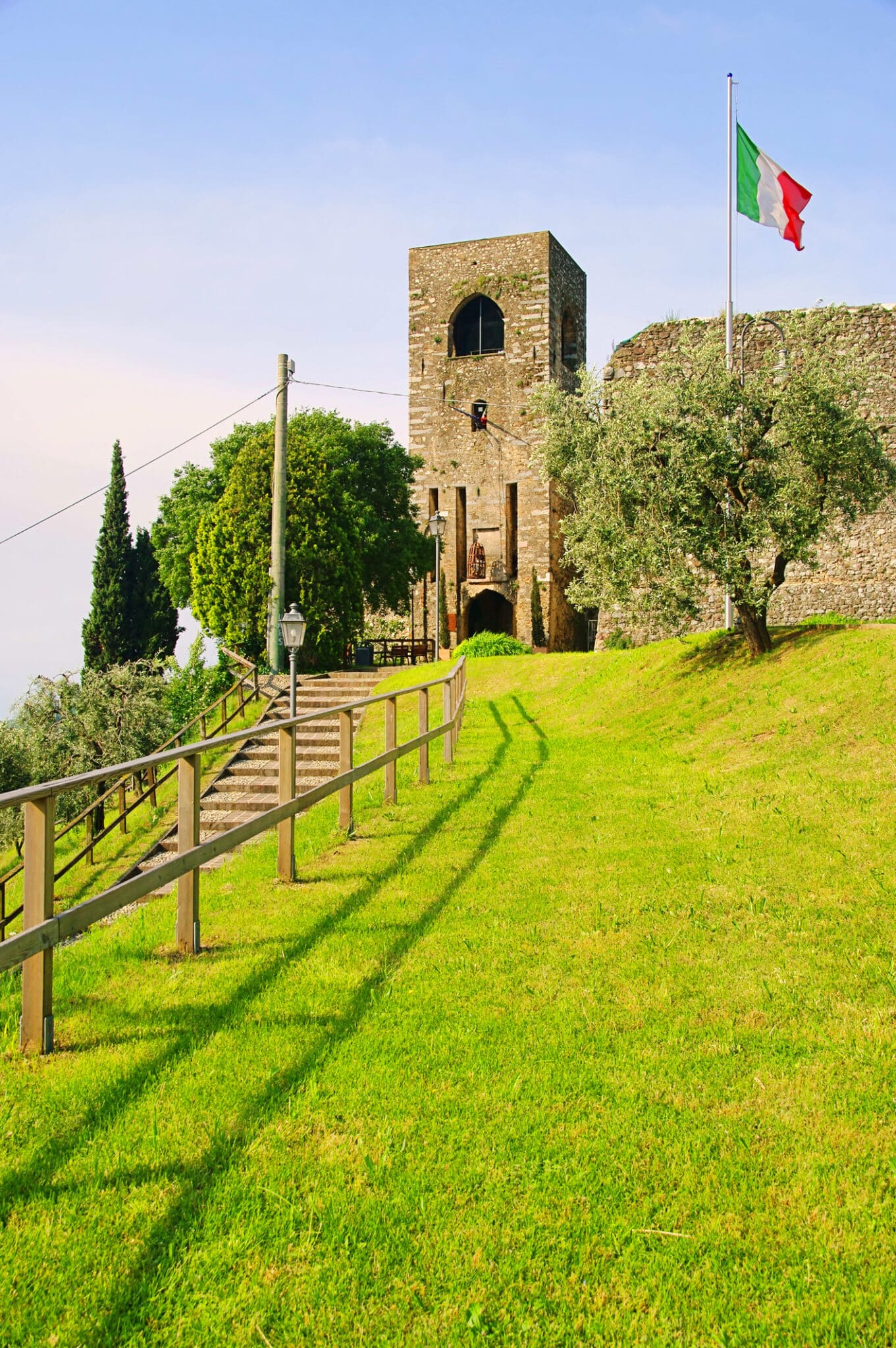 Antica torre italiana con bandiera su prato verde
