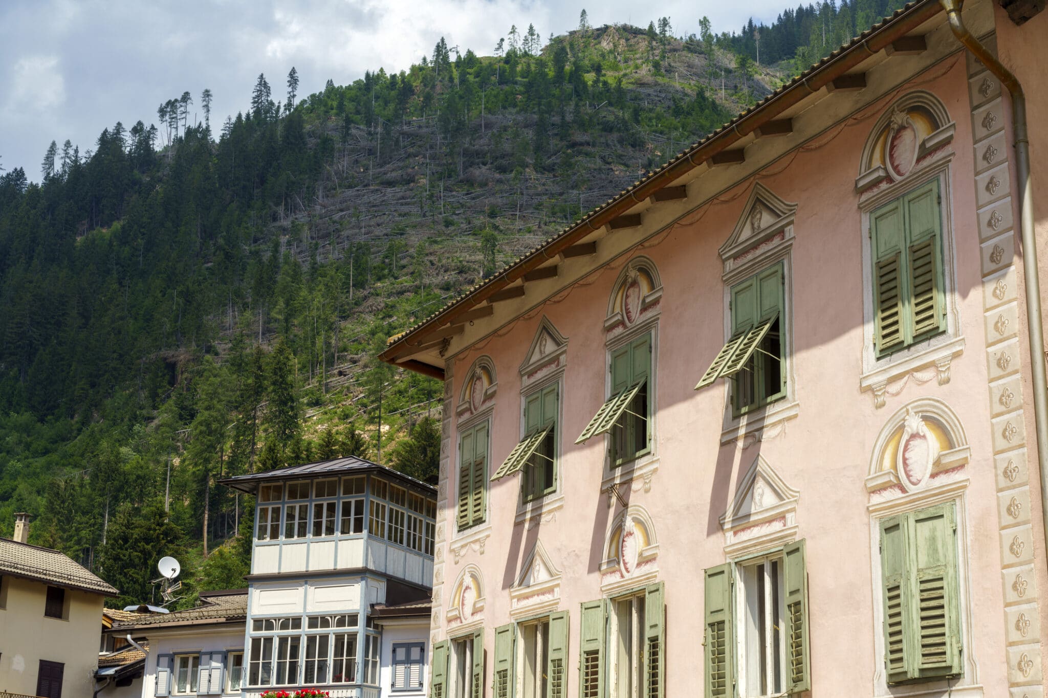 Casa vecchia con finestre verdi e montagna sullo sfondo