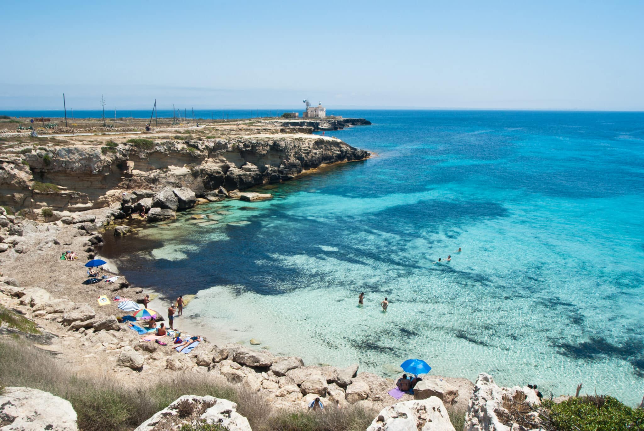 Cala di acqua cristallina con persone e ombrelloni