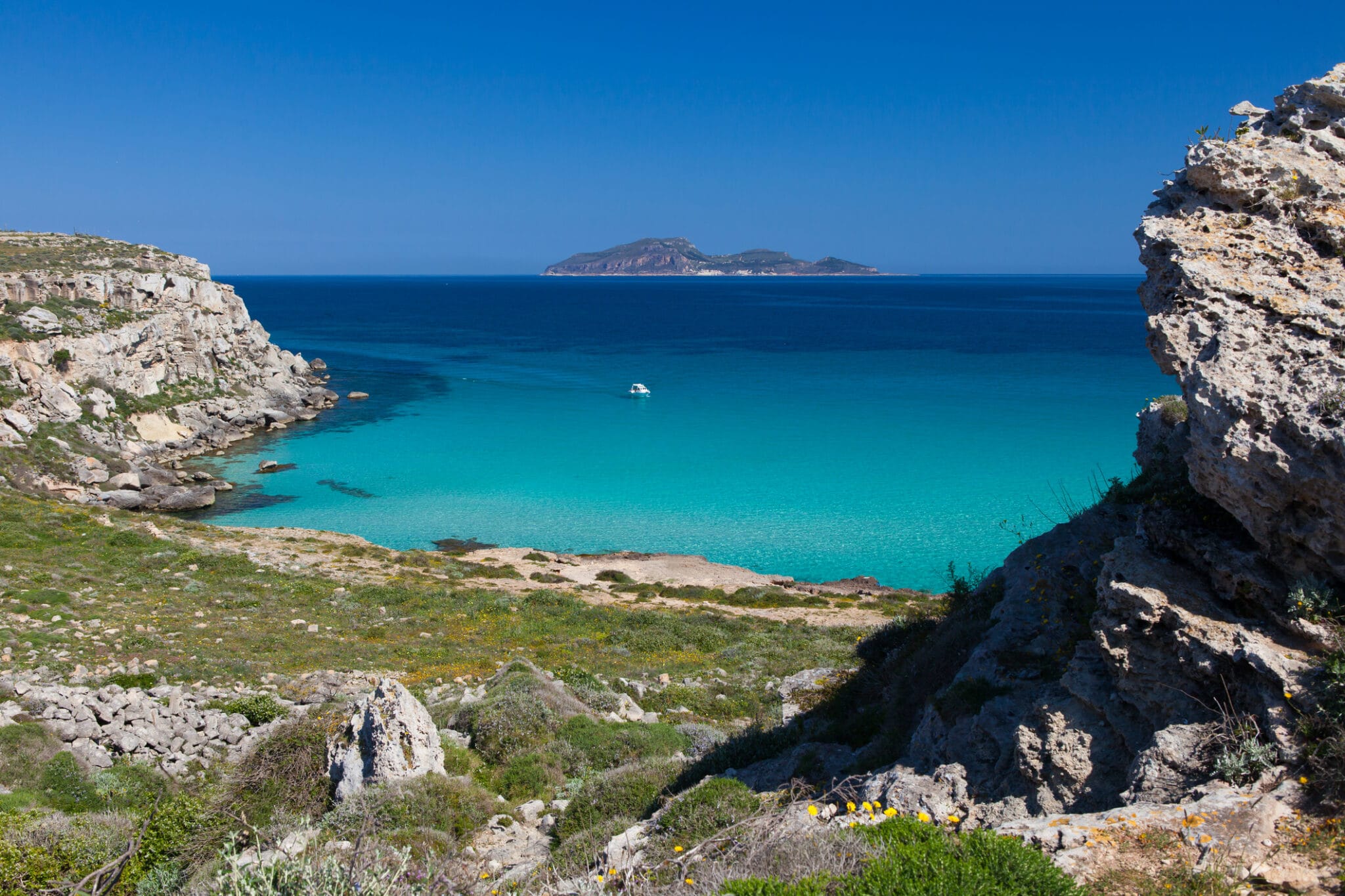 Scogliere e mare turchese con isola all'orizzonte
