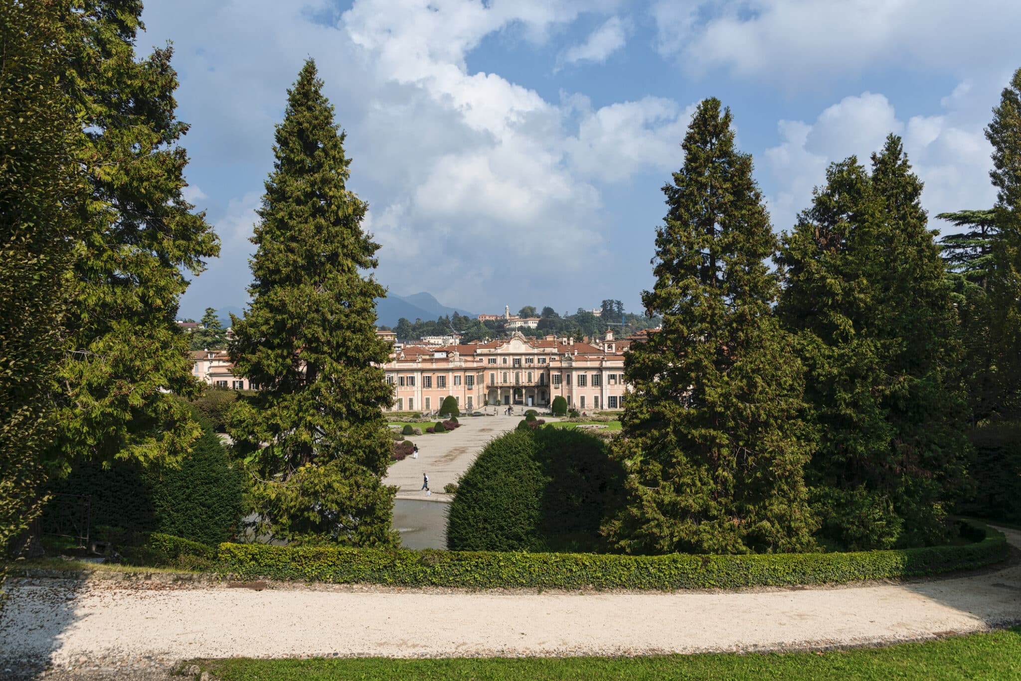 Villa storica con giardino rigoglioso e montagne sullo sfondo