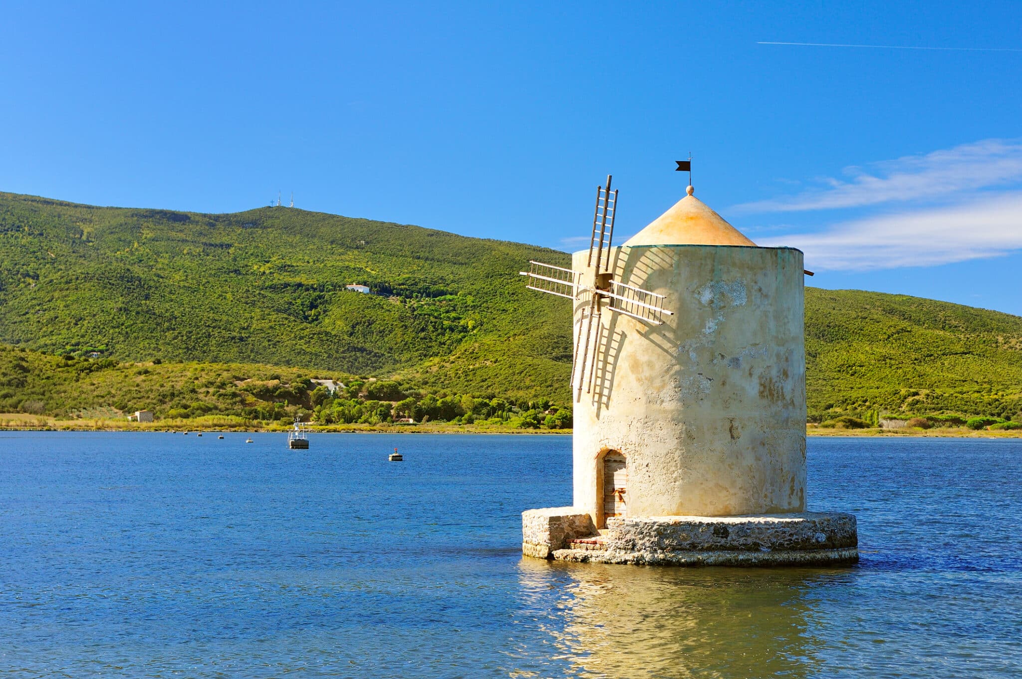 Mulino a vento storico sul lago, colline verdi sullo sfondo