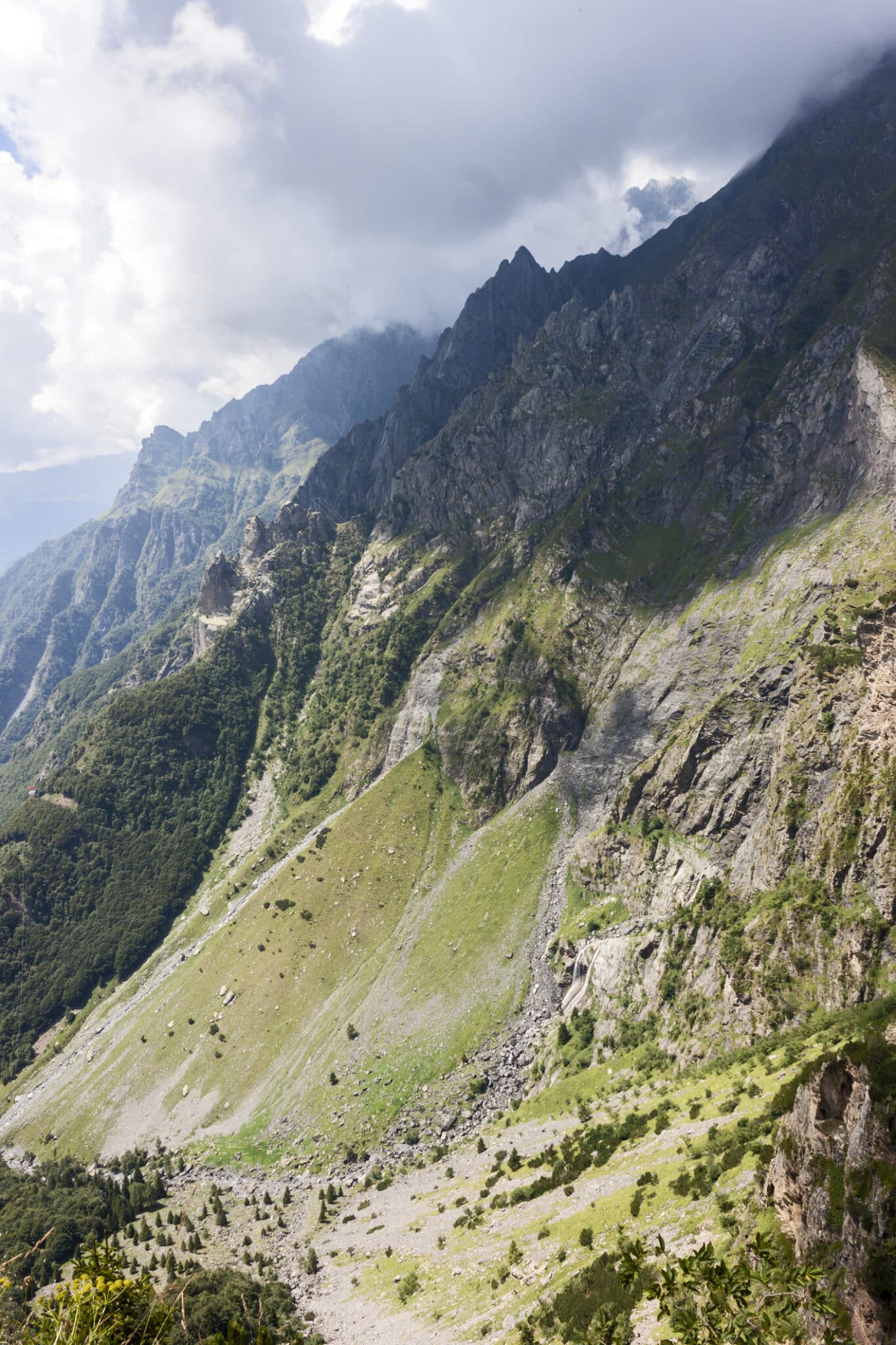 Panorama montano verde e roccioso sotto cielo nuvoloso