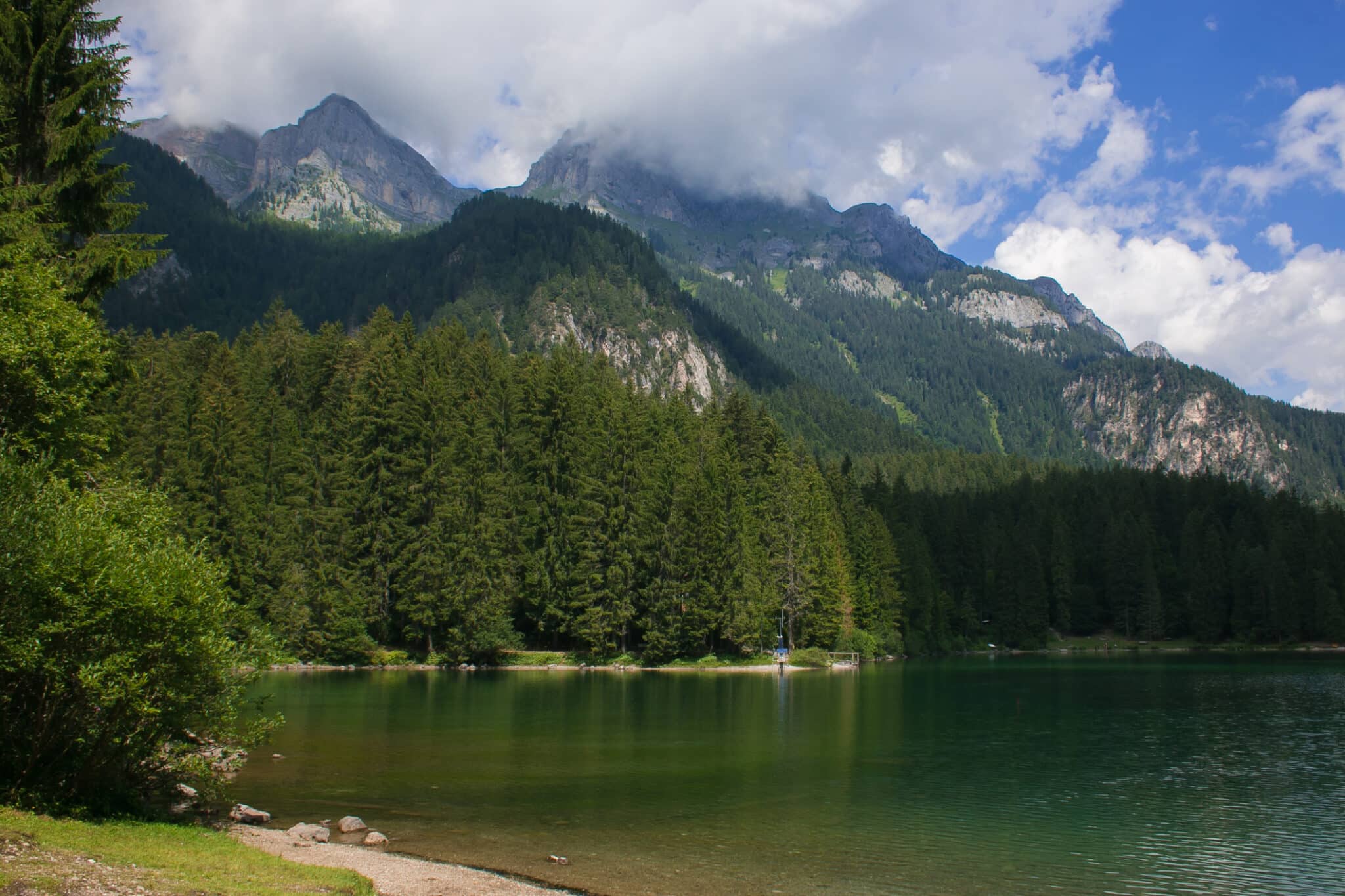 Lago alpino con foreste e montagne nuvolose