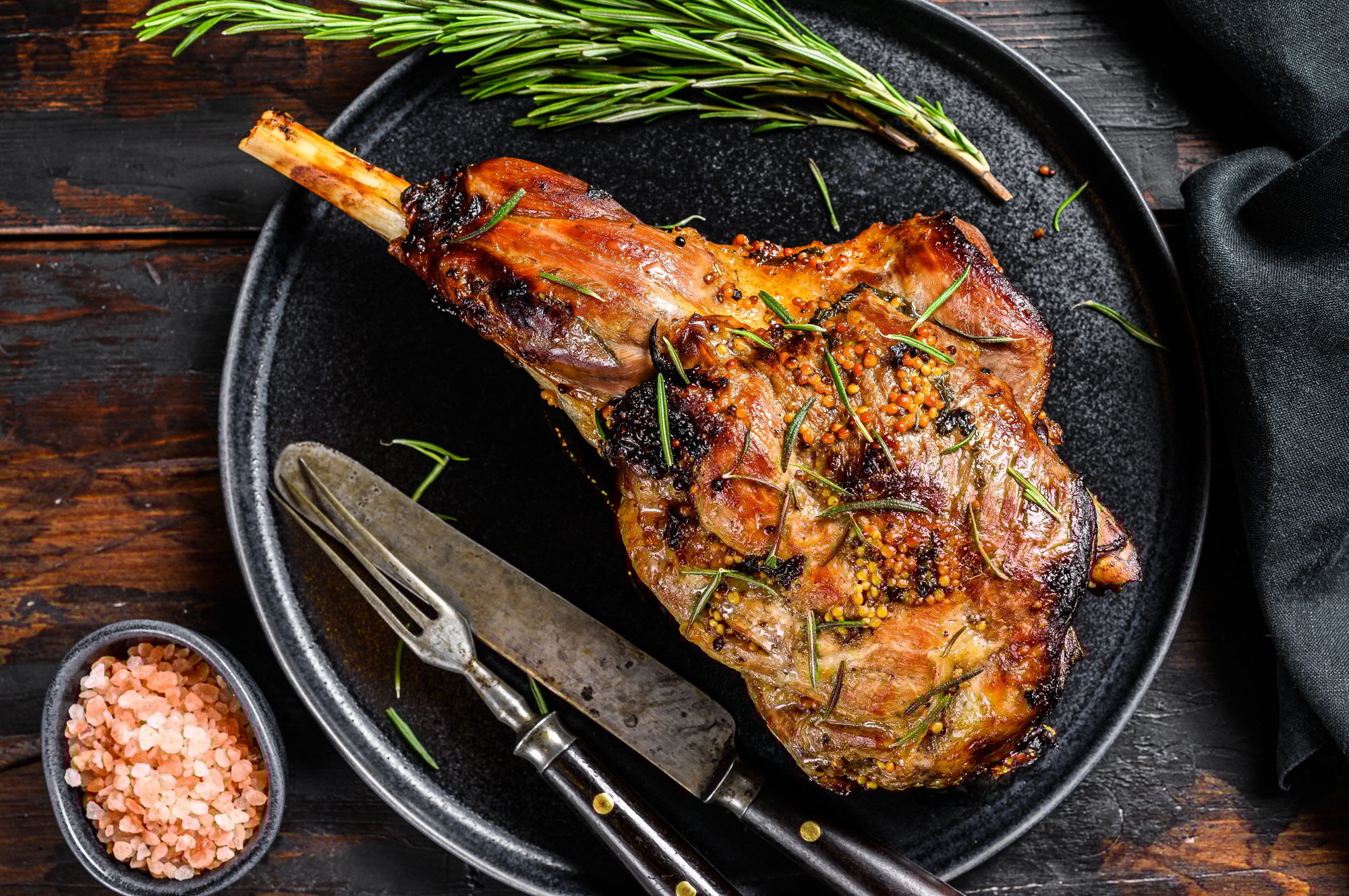 Cosciotto di agnello al forno con rosmarino servito su piatto rustico, piatto tipico di Pasqua in Italia.